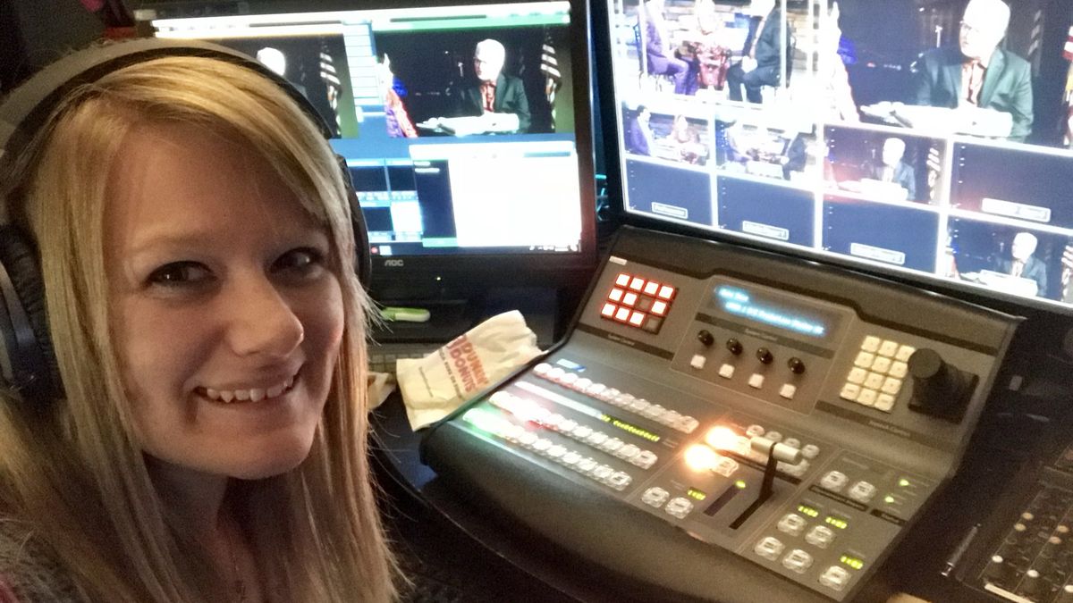 A volunteer seated at a video switcher with a multiviewer wall behind her